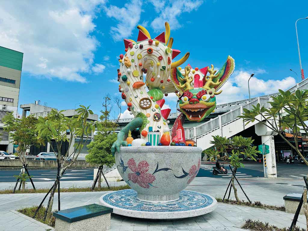 進入環南市場首先映入眼簾的是，以本地與外來食材交錯而成的龍形雕塑作品《紫氣東來》，龍身表面以麵條造型呈現細膩紋理，搭配各式陶瓷食材，象徵市場的生命力與文化流動。（圖／臺北市文化局提供）